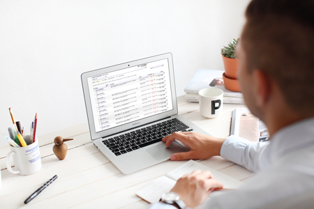 Business person at their desk with laptop and papers in front of them.